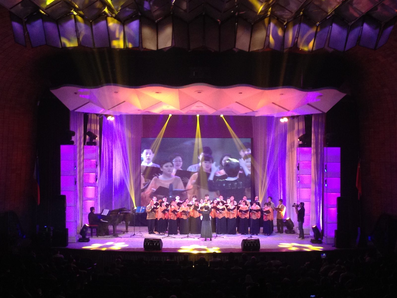 Live stage performance supported by a large projection screen and magenta lighting
